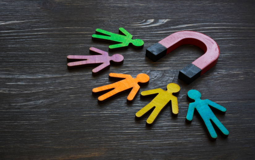 Colorful wooden figures drawn to a magnet, symbolizing audience engagement and faceless video strategies for YouTube growth.